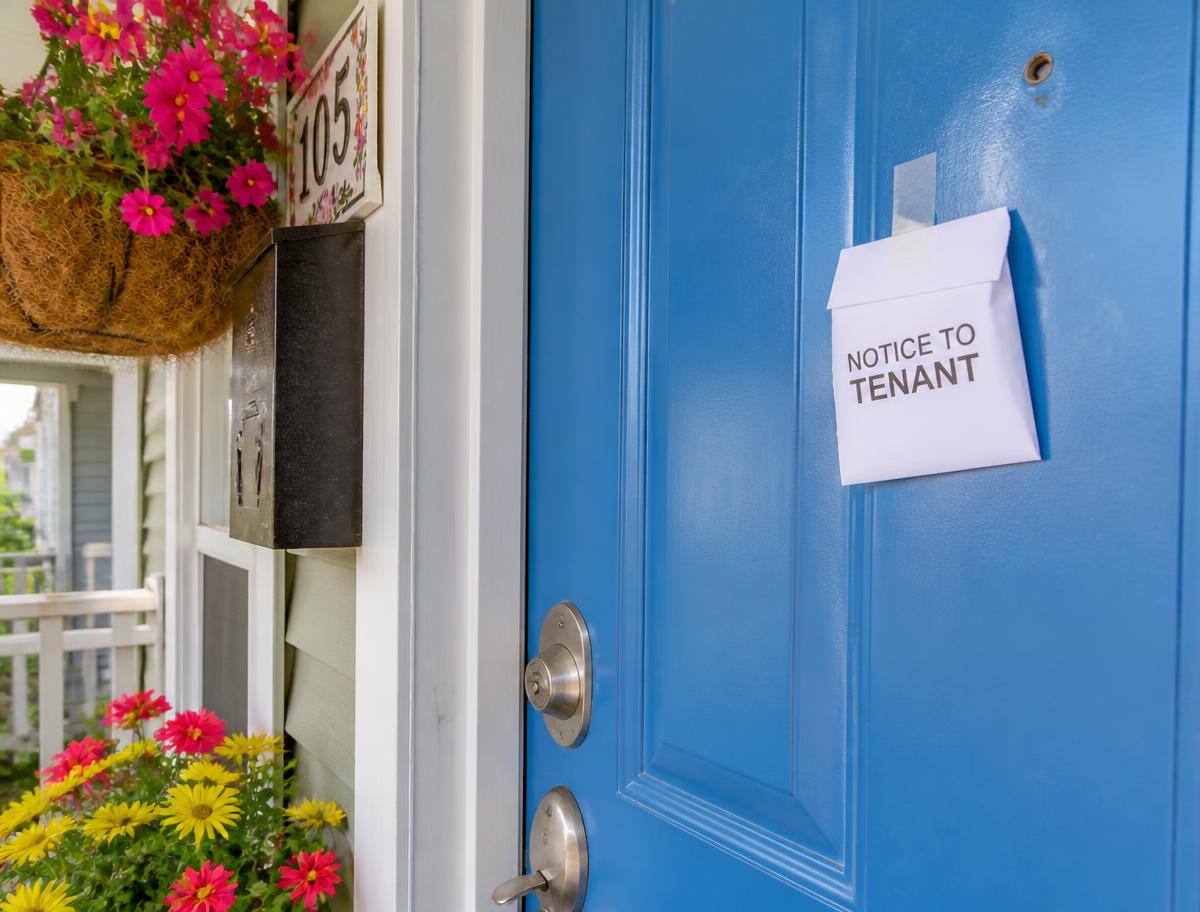 Notice envelope taped to a blue rental front door